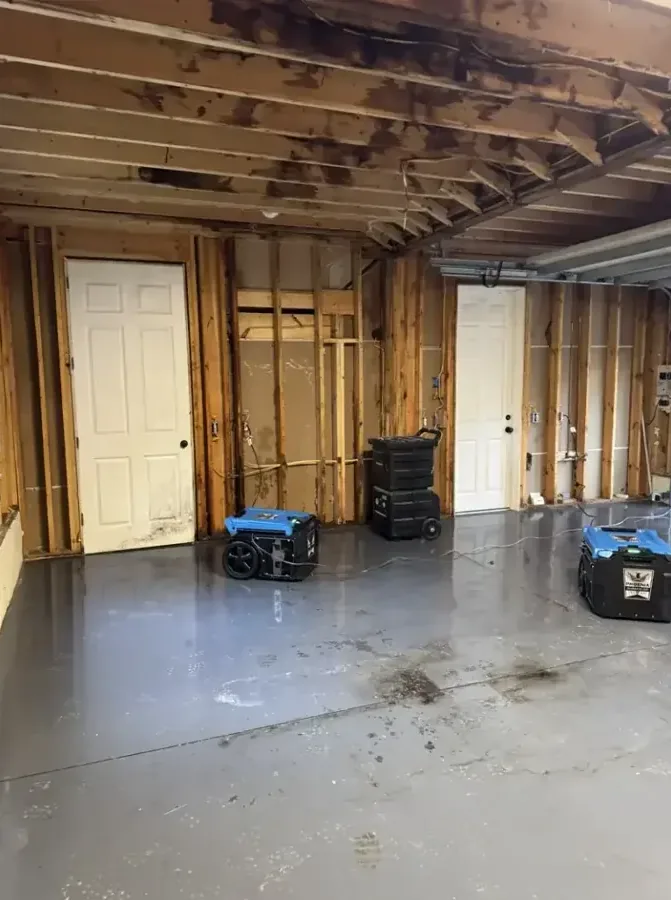 Dehumidifiers positioned across a gutted lower room during structural drying