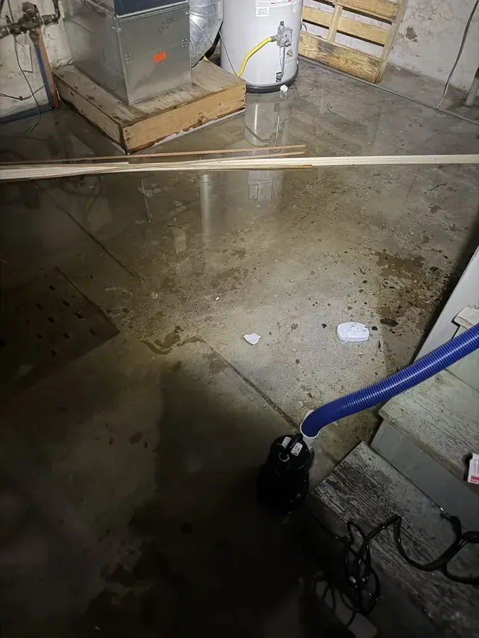 Water pools around a blue extraction wand on an exposed utility room floor