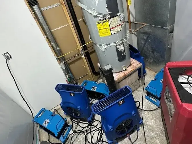 Blue air movers drying the floor around a water heater