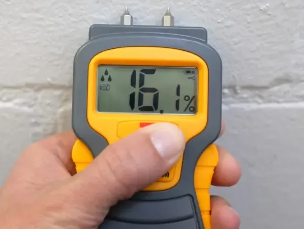 A moisture meter checks a wall surface during an interior drying assessment.
